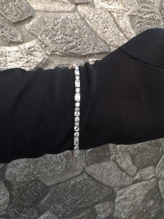 Silver bracelet on a person's wrist against a stone wall background
