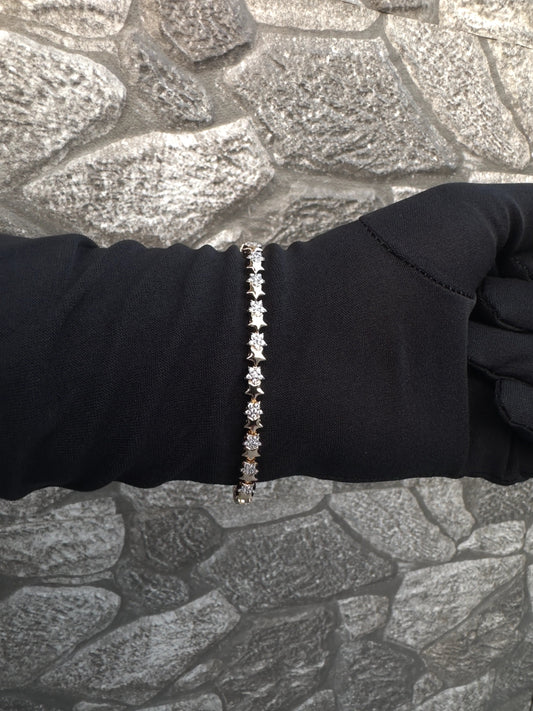 Bracelet with small stones on a person's wrist against a textured stone wall background