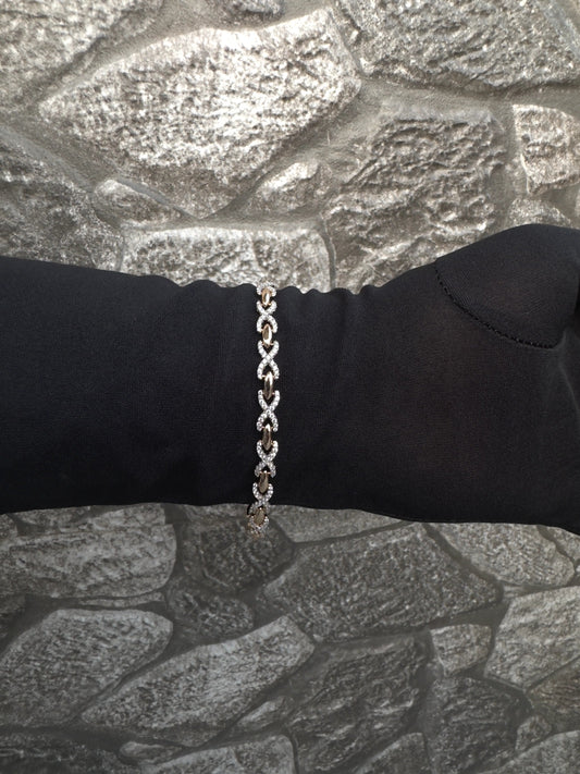 Silver chain bracelet on a black wrist against a stone wall background