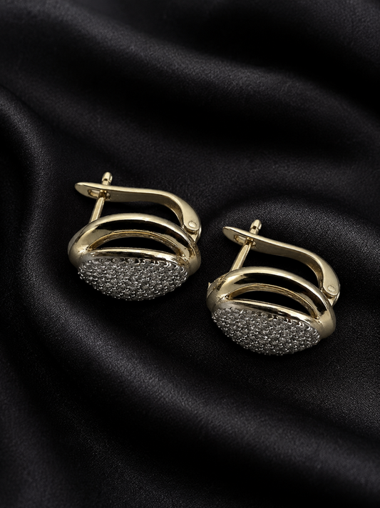 Gold and black earrings on a black fabric background