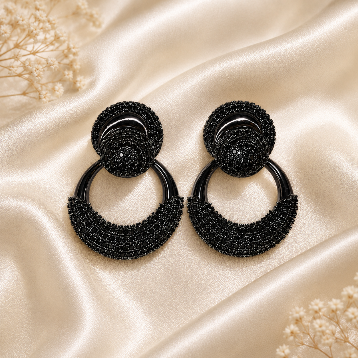 Black beaded hoop earrings on a beige fabric background