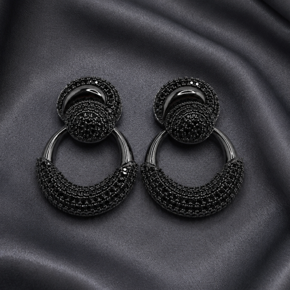Black earrings on a black satin background