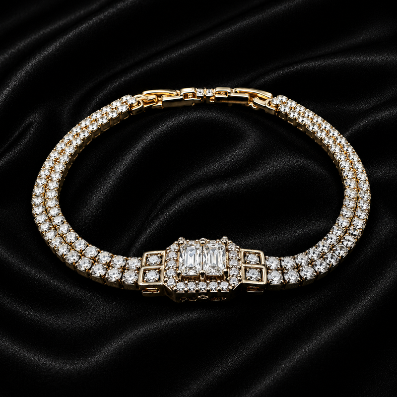 A gold-plated double-row diamond tennis bracelet with a rectangular baguette-cut center stone and square accent stones, displayed on a black satin background.
