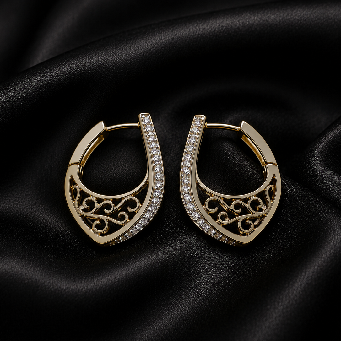 Gold hoop earrings with intricate designs on a black satin background