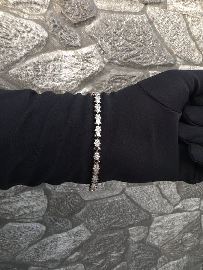 Bracelet with small stones on a person's wrist against a textured stone wall background