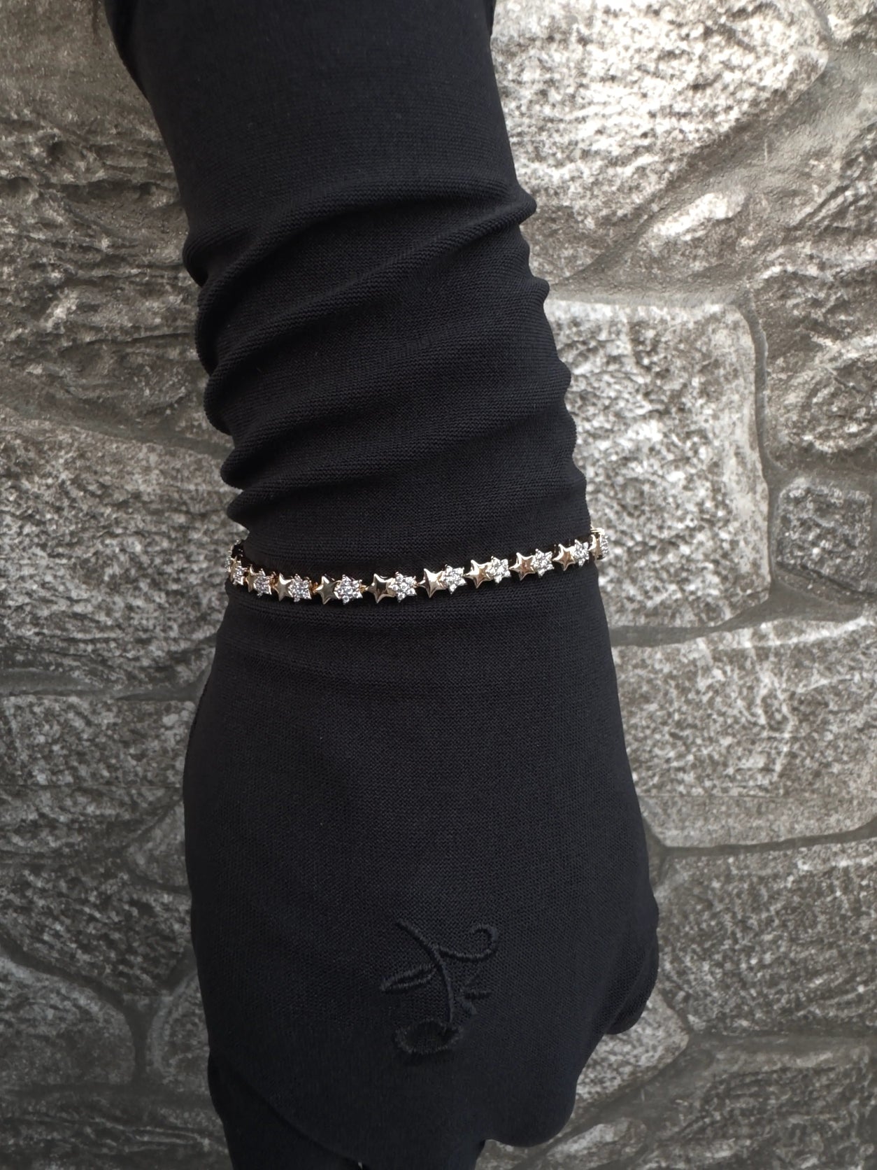 Bracelet on a gloved hand against a stone wall background