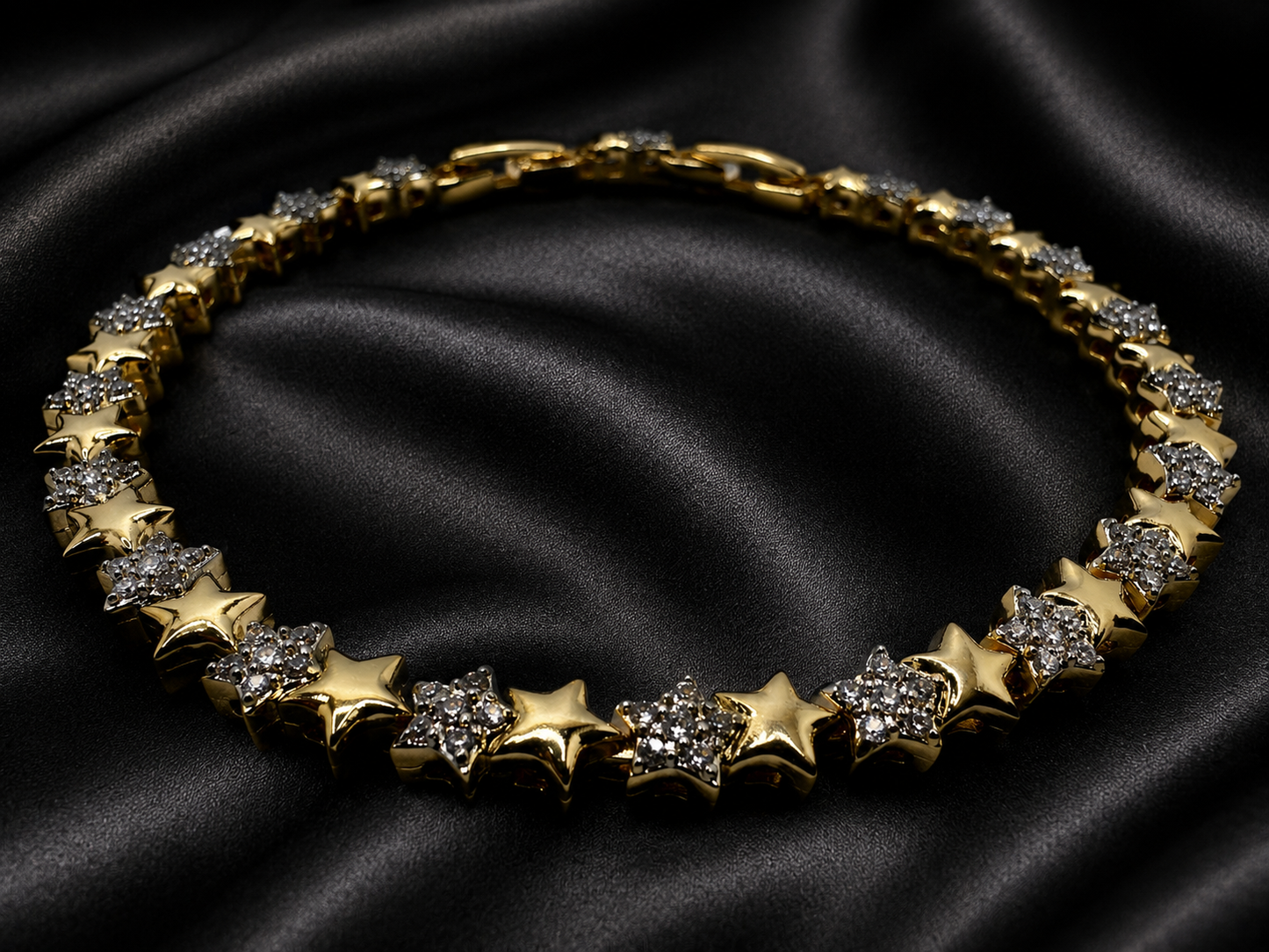 Gold necklace with star-shaped pendants on a black satin background