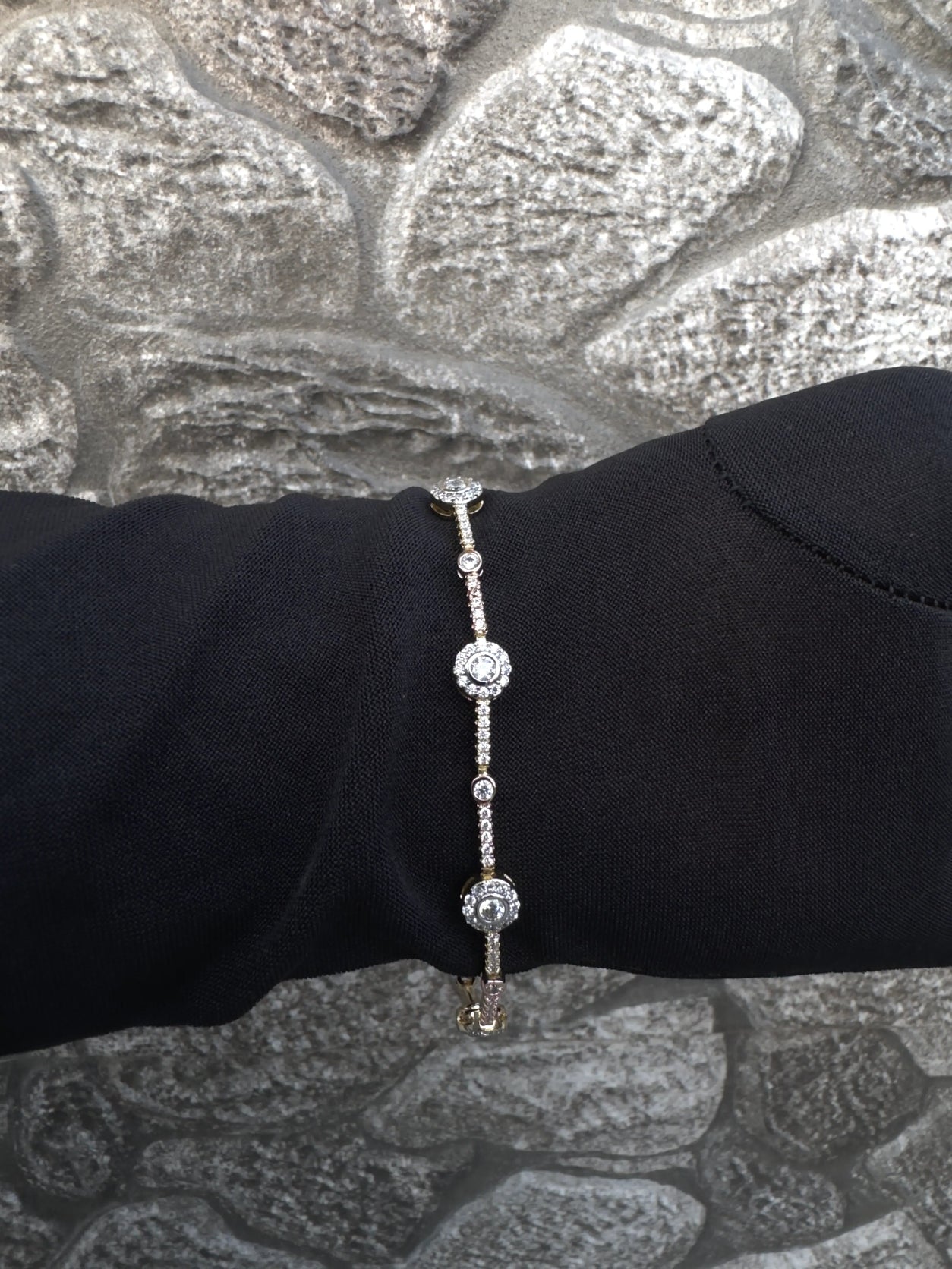 Silver bracelet on a black mannequin arm against a textured silver background