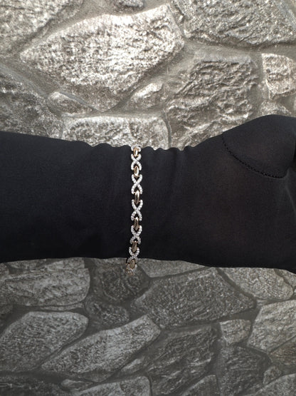 Silver chain bracelet on a black wrist against a stone wall background