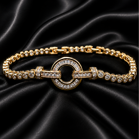 A gold-plated chain bracelet with a central circular ring and pavé-set clear stones, displayed on a draped black satin fabric background.