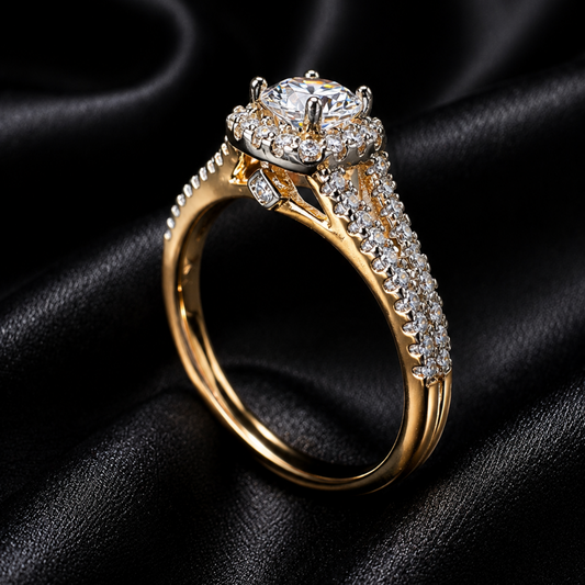 A yellow gold halo ring with a large round-cut center stone and pavé-set side stones, displayed on a draped black satin fabric background.