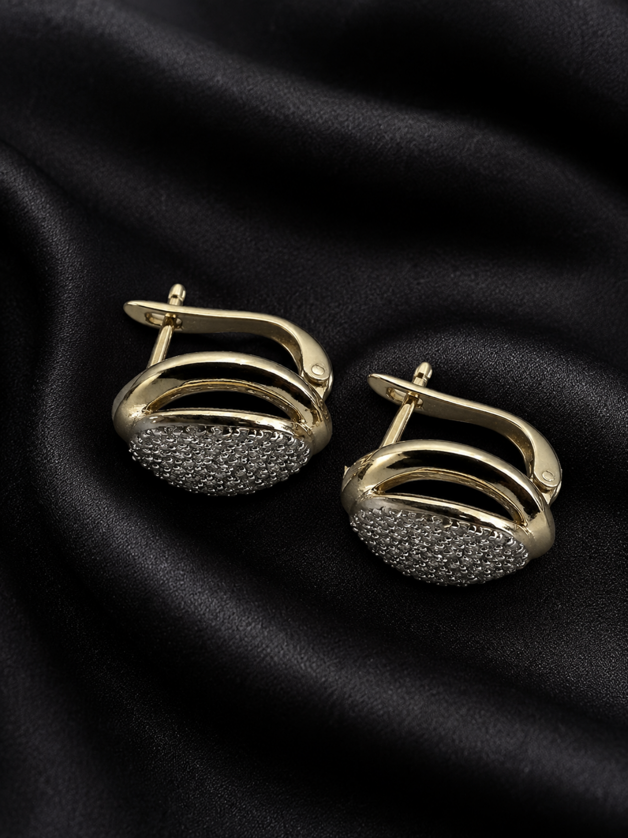 Gold and black earrings on a black fabric background