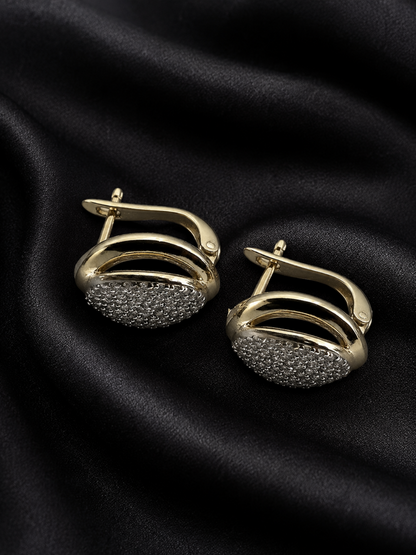 Gold and black earrings on a black fabric background