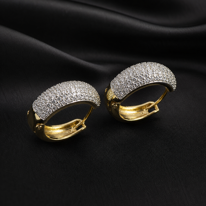 Pair of gold hoop earrings with diamond-like stones on a black fabric background