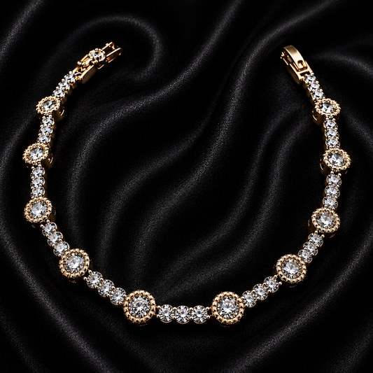 A gold tennis bracelet with clear round-cut stones, arranged in a curved line on a draped black satin fabric background.