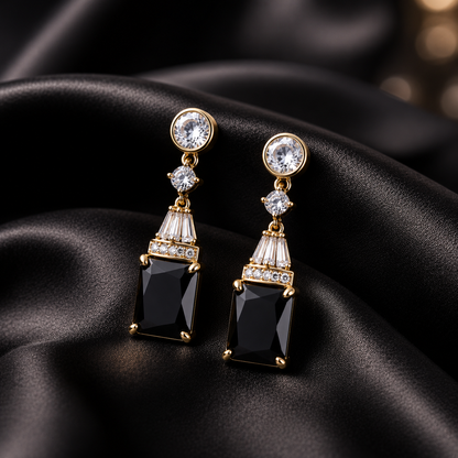 Pair of earrings with black gemstones and gold accents on a black satin background