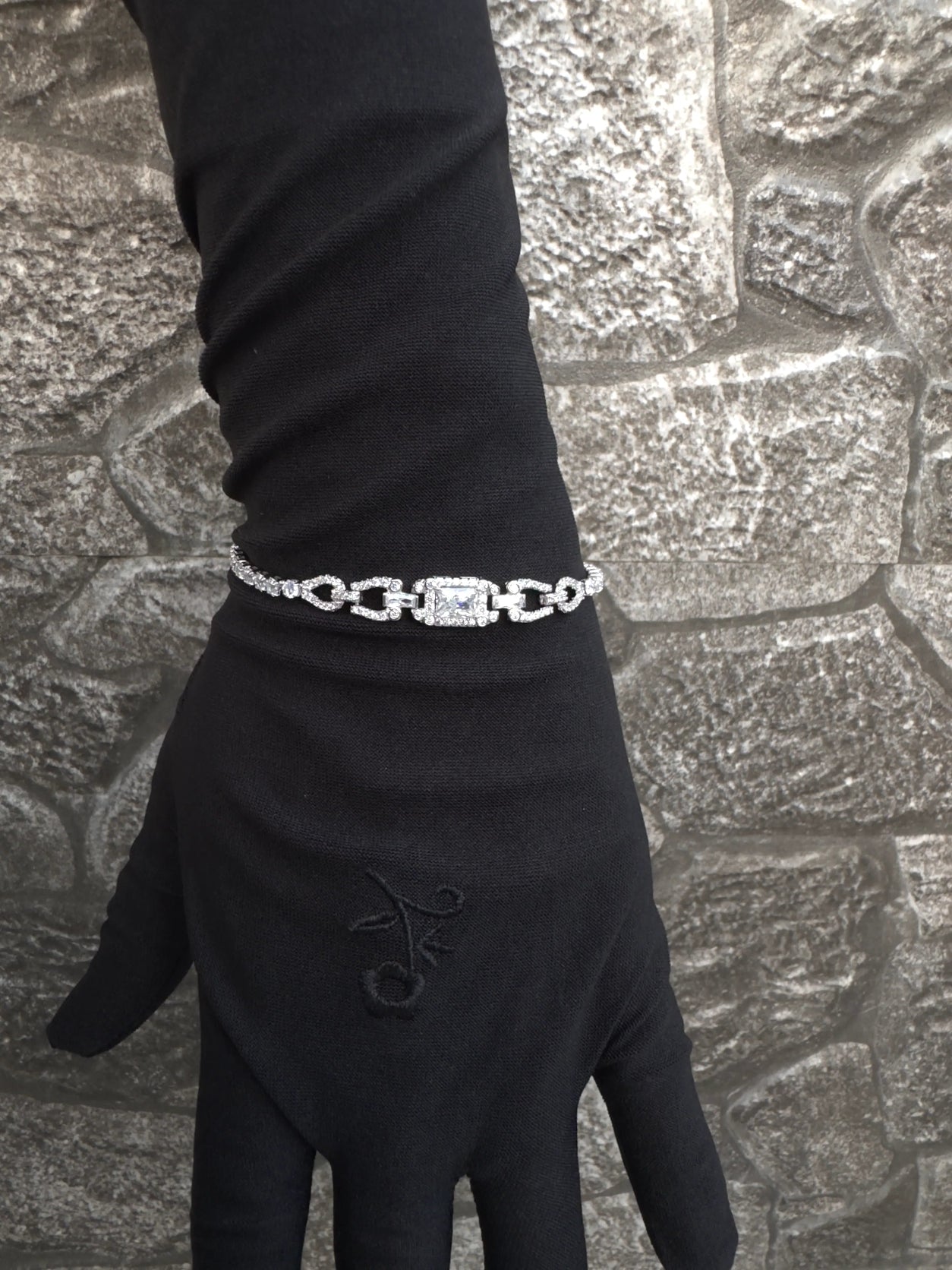 Black glove with a silver bracelet on a textured stone surface