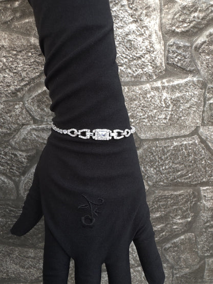 Black glove with a silver bracelet on a textured stone surface