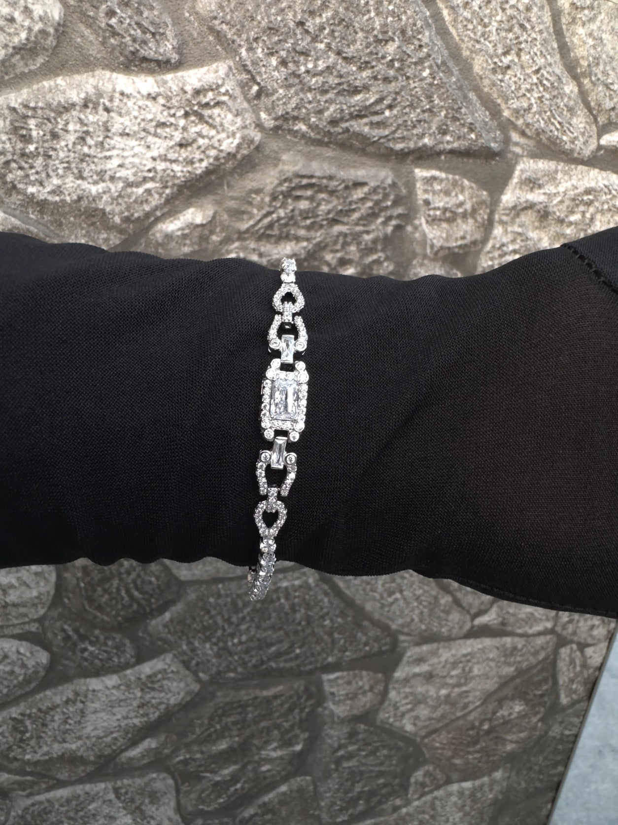 Silver bracelet on a person's wrist against a textured wall background